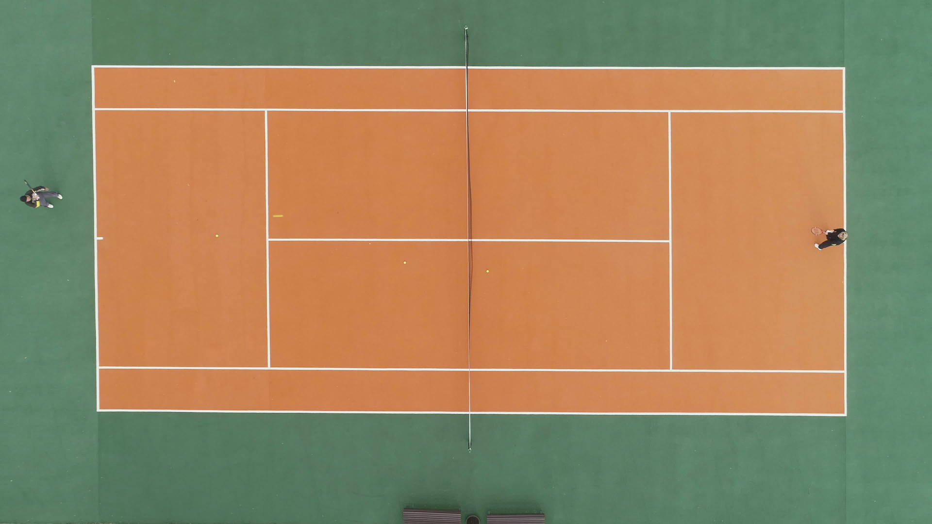 在绿色和橙色的球场上球员们在空中垂直射程最高的无人机上打网视频的预览图