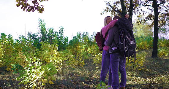 在一个阳光明媚的下午一对年轻的游客在秋天的森林里留着金发女孩视频的预览图