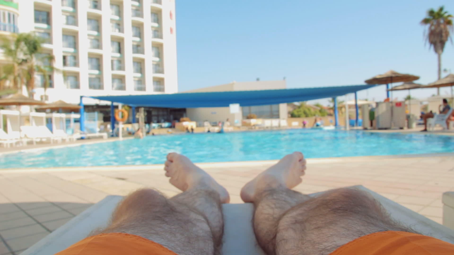 男人在游泳池的阳光下放松和晒太阳视频的预览图