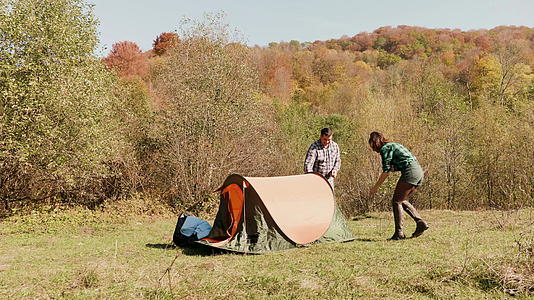 年轻夫妇互相帮助建造露营帐篷视频的预览图