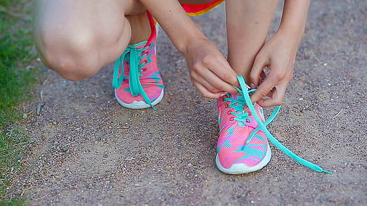 年轻女性穿着明亮的粉色和蓝色鞋子的手跑鞋——紧贴鞋带视频的预览图