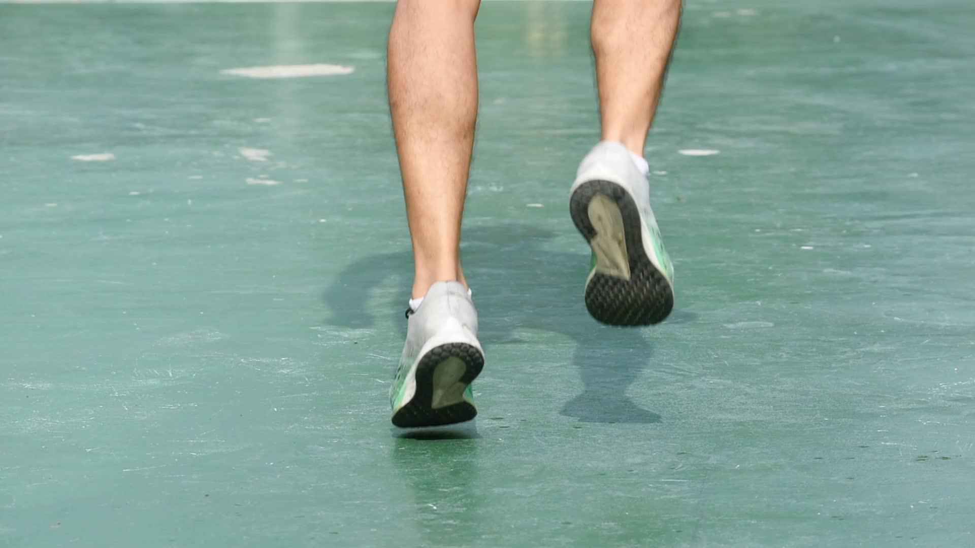 穿着运动鞋跑步的男人的腿固定在绿色背景上姿势固定视频的预览图