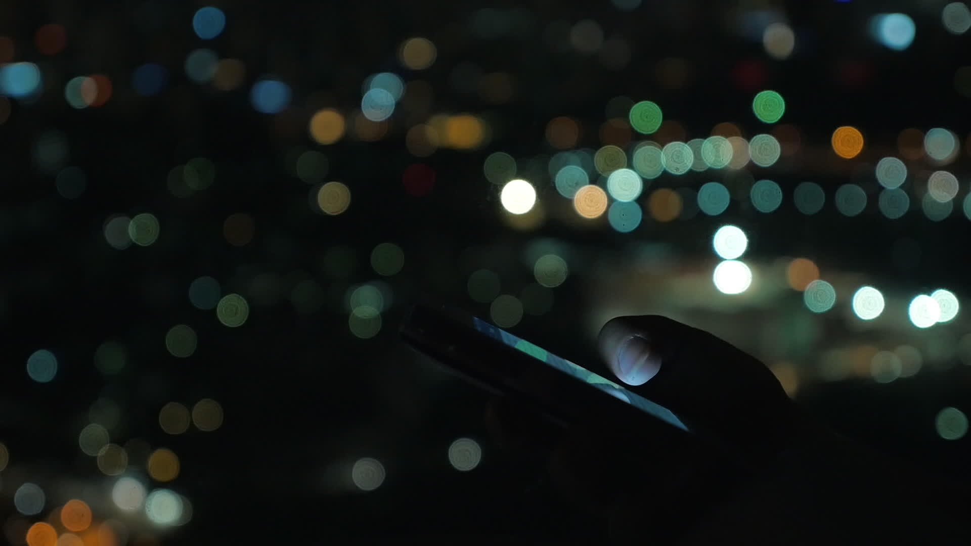 女性用手机对抗夜间模糊的城市景观视频的预览图