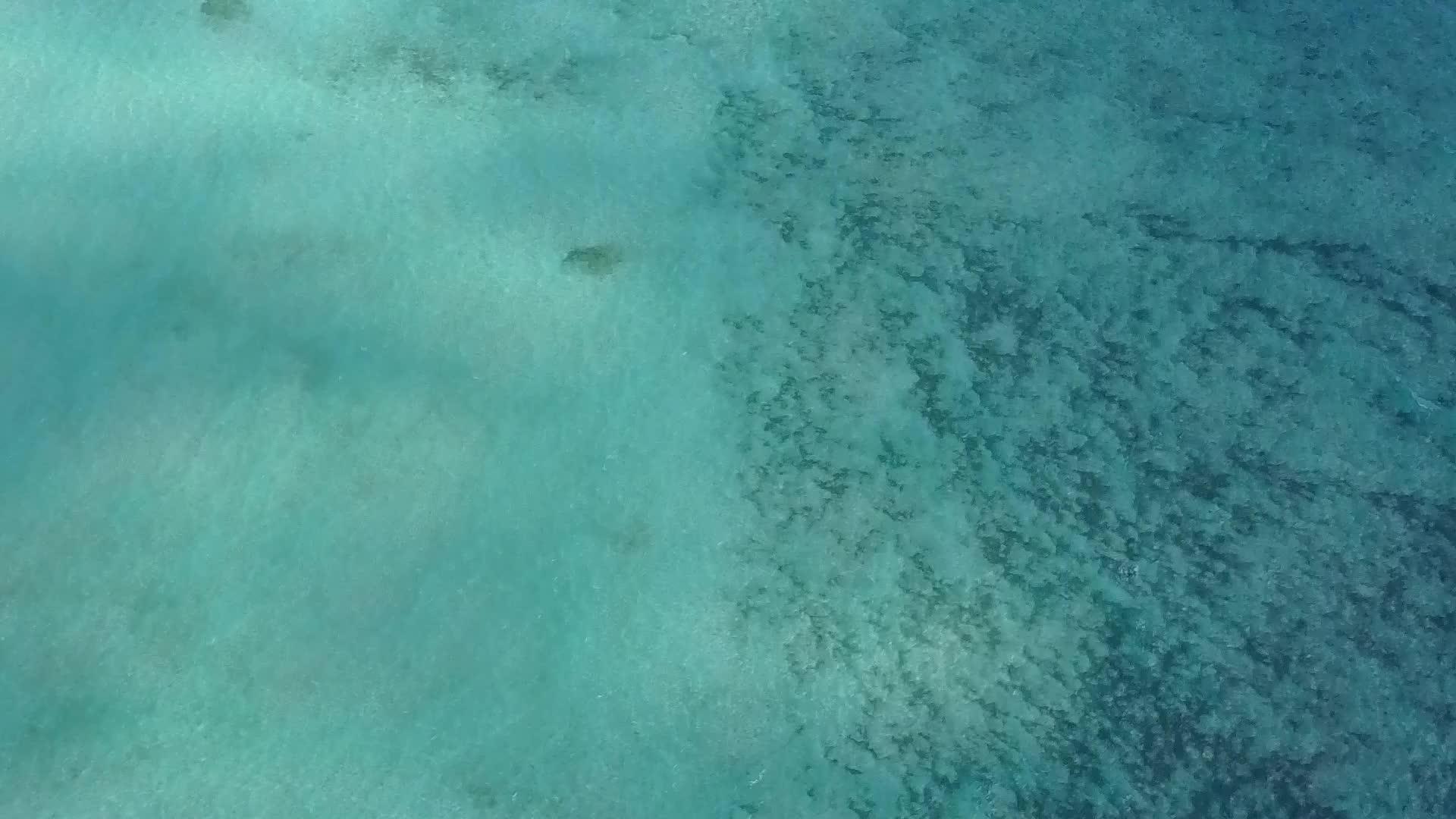 蓝色的海平面以白色的沙子为背景冲出海滩绕过一片蓝色的海洋视频的预览图