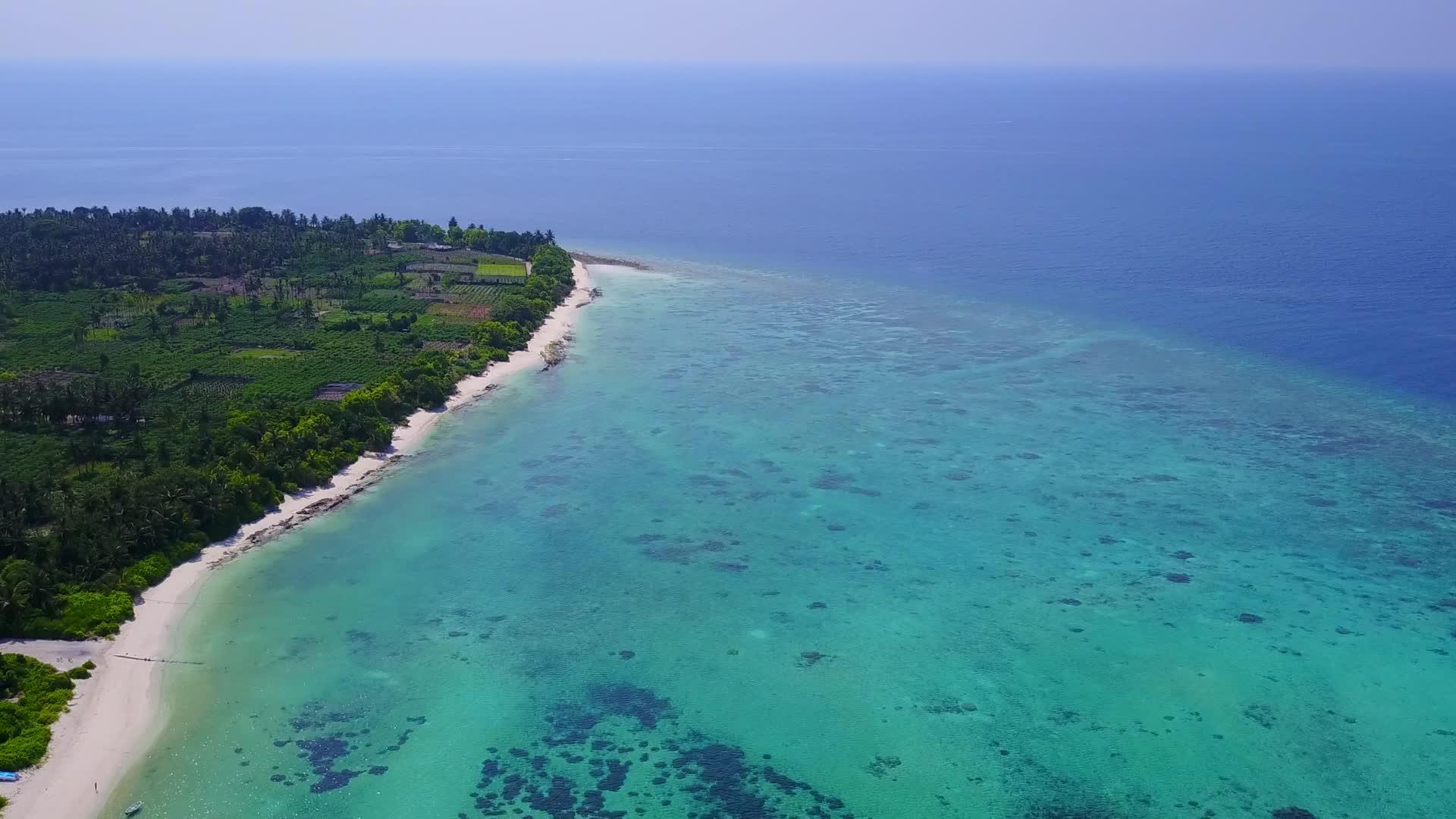 白沙背景蓝海海岸海滩空中无人机全景视频的预览图