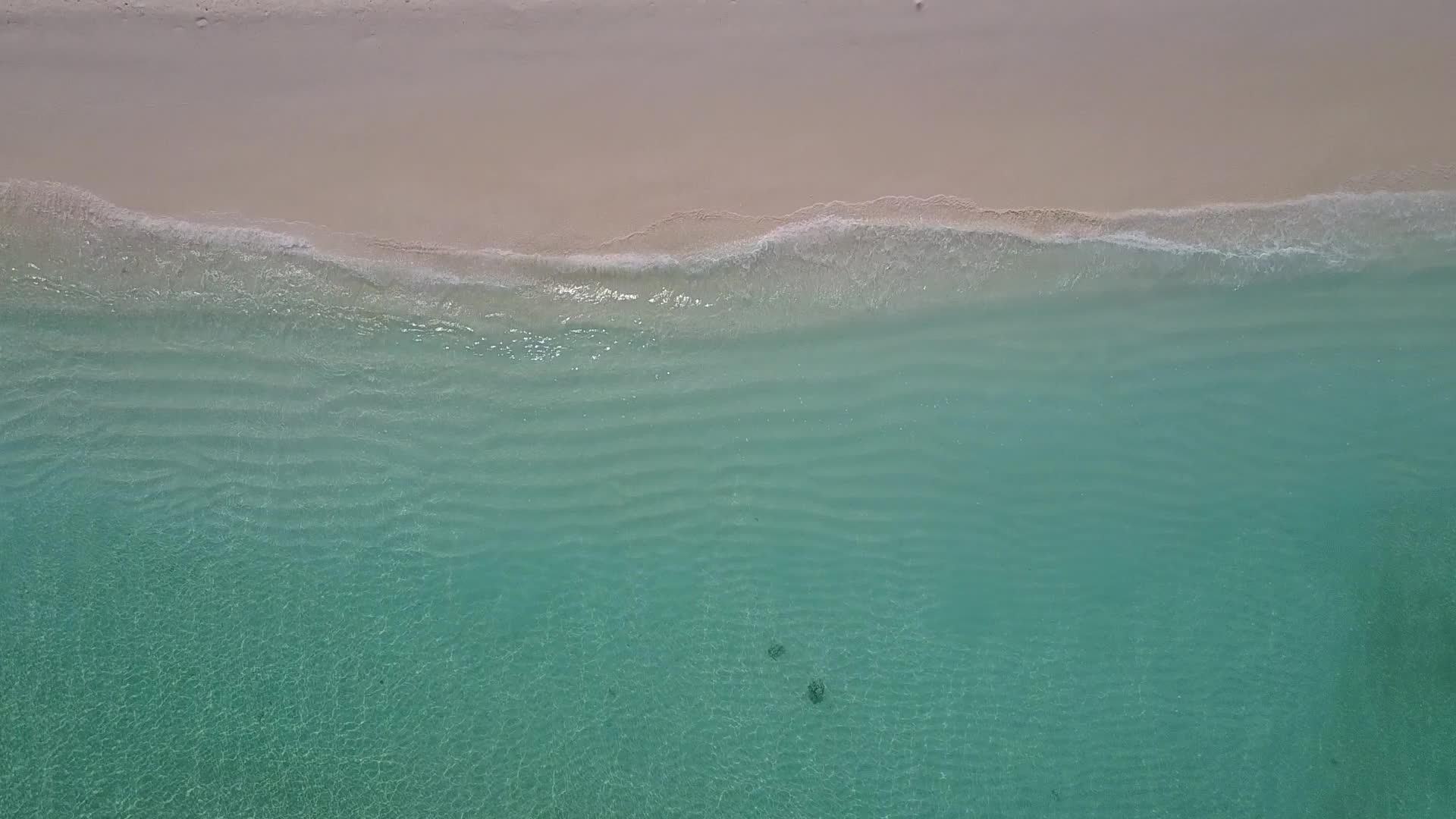 白沙背景蓝海海岸线海滩度假空中景观视频的预览图