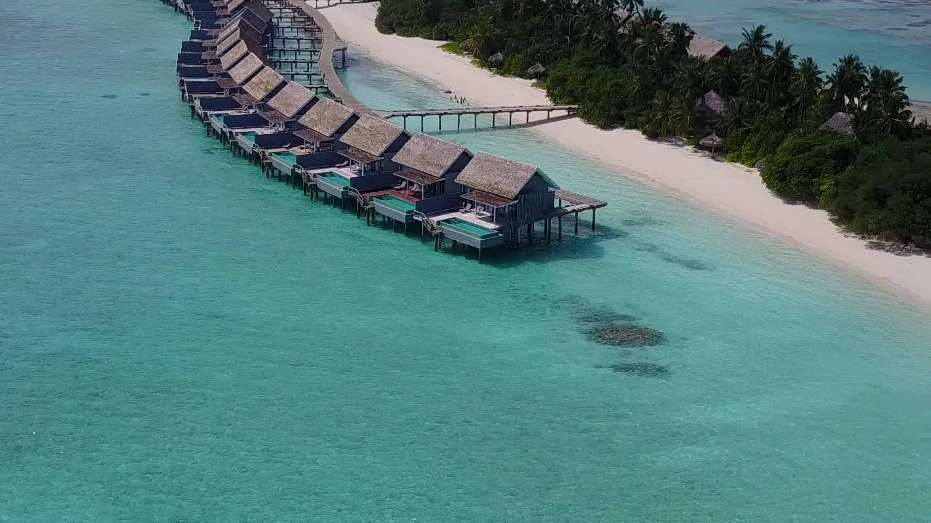 蓝绿环礁湖和白色沙滩背景下的宁静度假胜地海滩视频的预览图