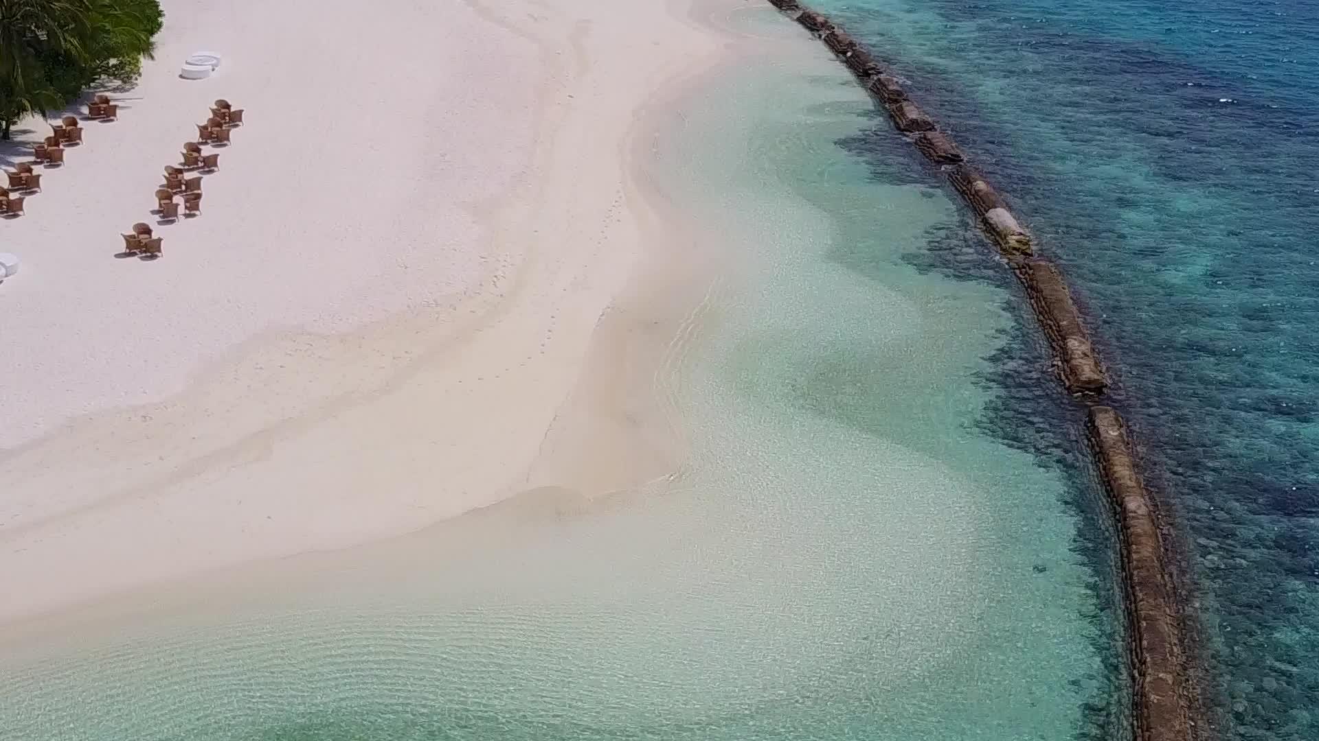 白沙背景背景下绿松石环礁湖在天堂湾海滩上冒险空中无人驾驶视频的预览图