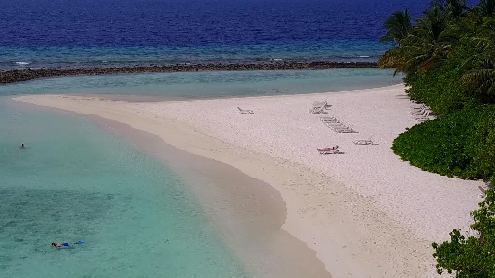 以蓝海和白沙为背景的美丽海岸海滩之间的空中旅游视频的预览图
