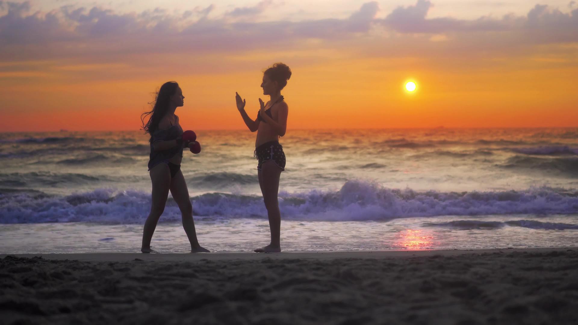 女青年在海滩日落时练习空手道视频的预览图