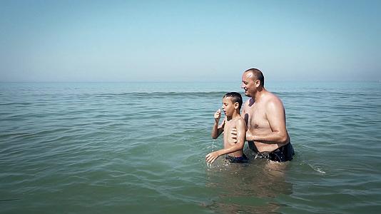 父亲把儿子扔在海滩上认为一个友好的家庭很慢视频的预览图