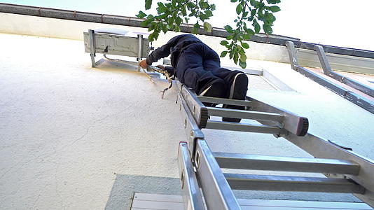 修复室外空调系统的年轻男技师站在铝阶梯上；视频的预览图