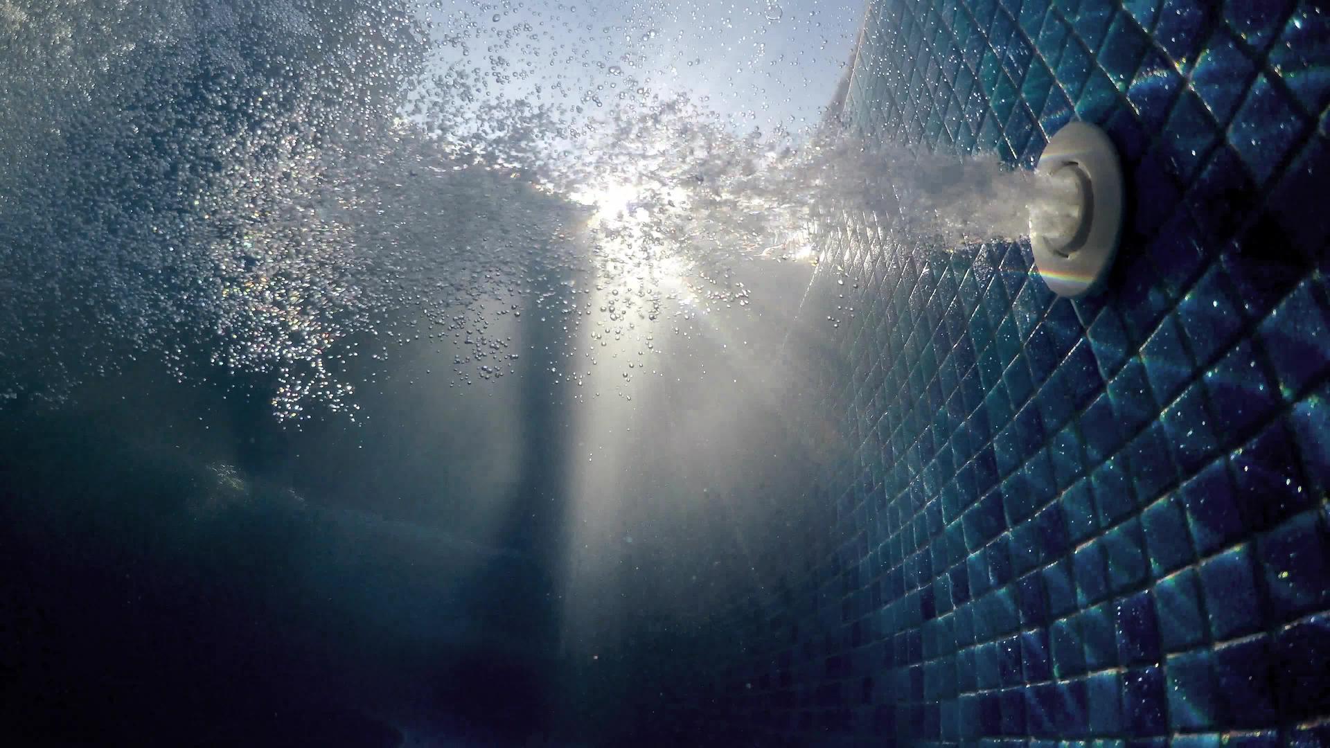 温泉游泳池中的空气泡和波浪水阳光照亮的水下风景视频的预览图