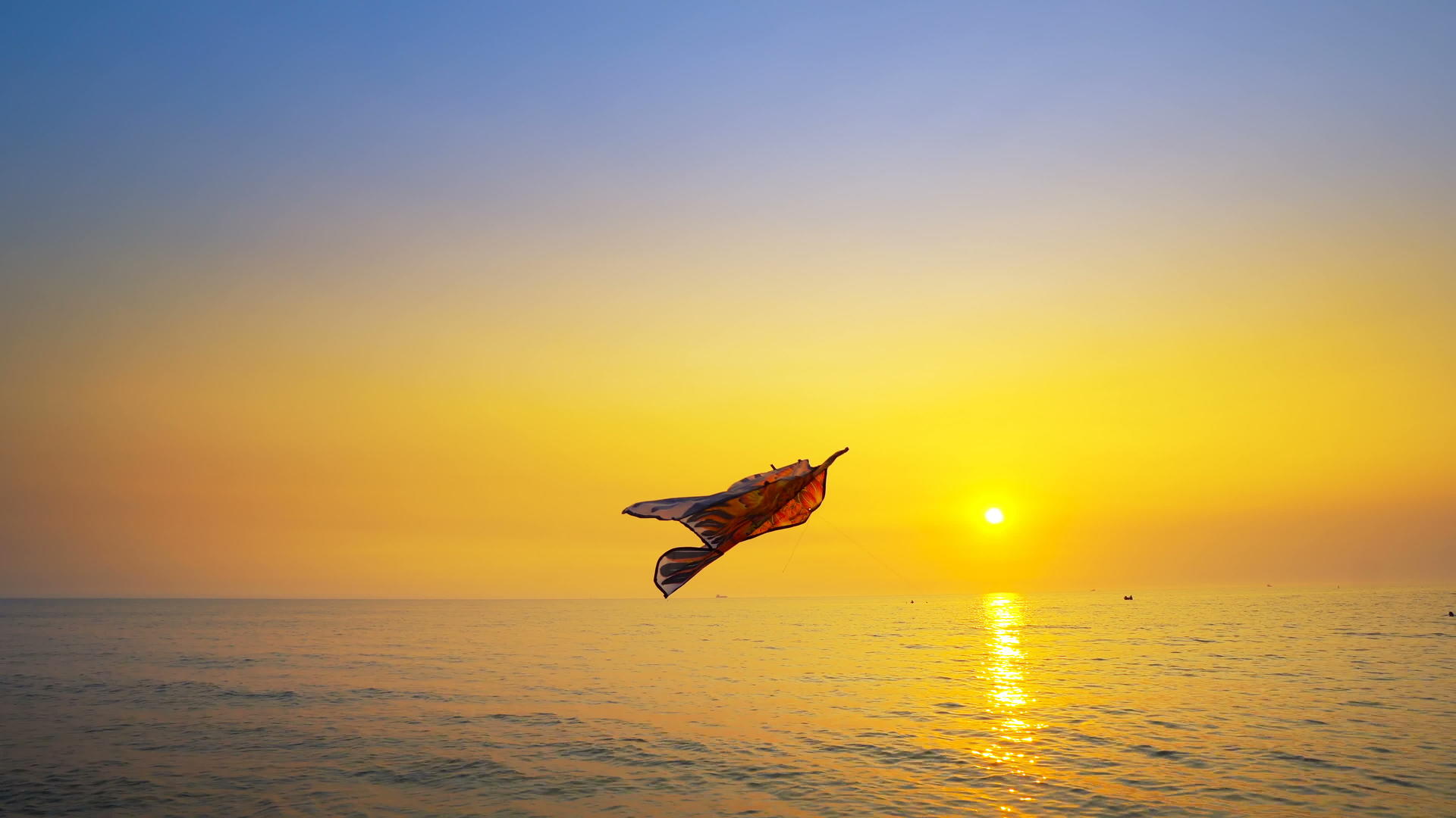 五颜六色的玩具风筝在空中高飞海边金色的太阳在天空中落日视频的预览图