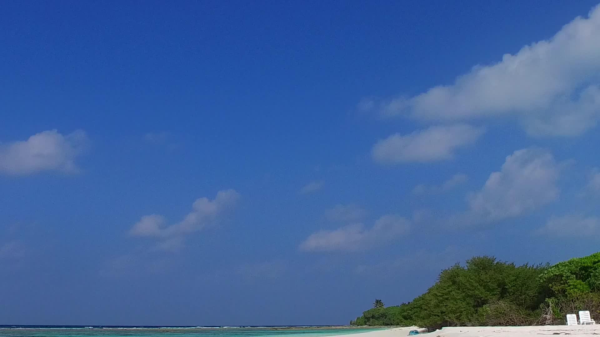 蓝色环礁湖和白色沙底背景附近的海岸海滩视频的预览图