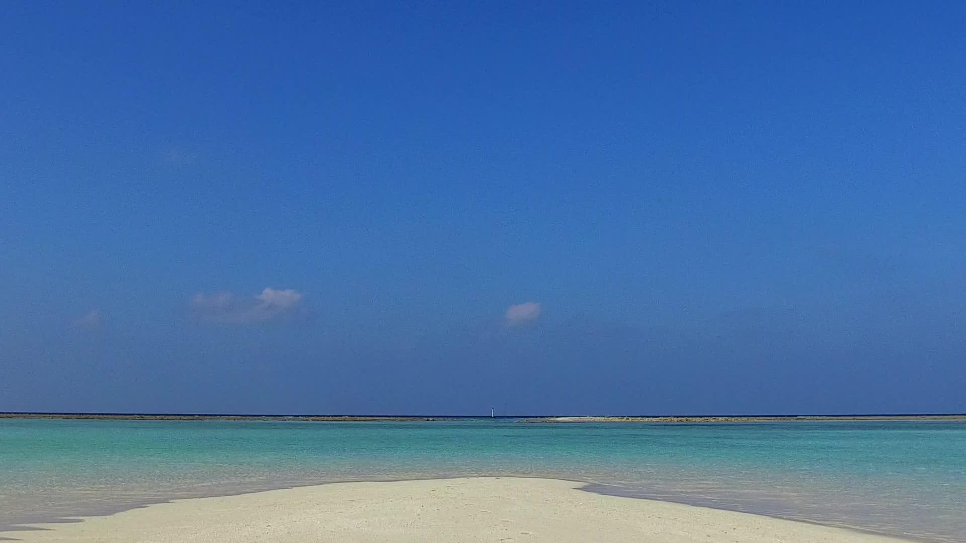 日出后蓝水和浅沙背景的蓝水打破了热带海滩的宽角航行视频的预览图
