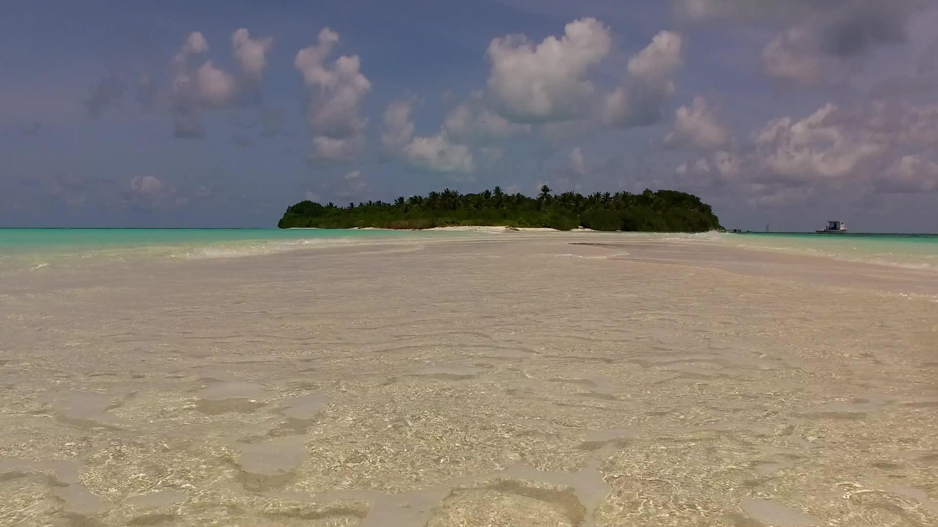 在阳光下以白沙为背景的绿色海洋紧密环绕着宁静的岛屿视频的预览图