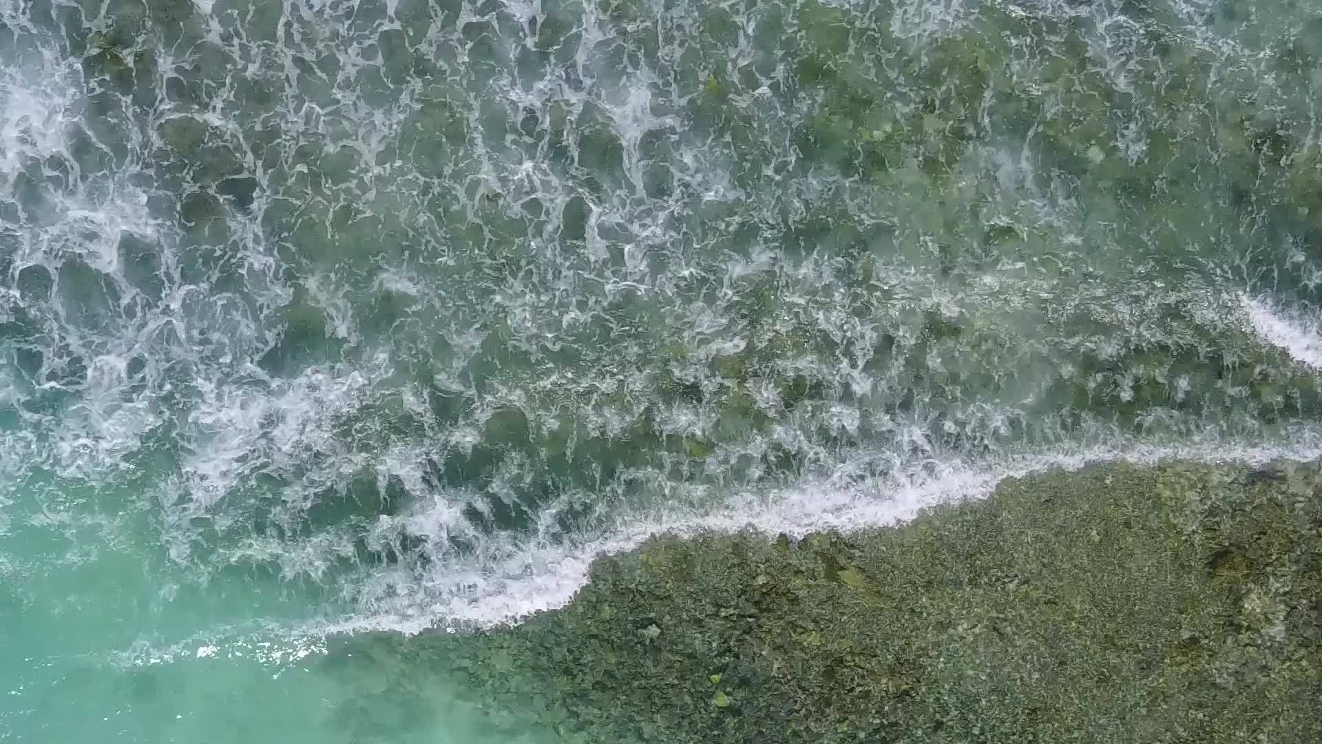 海滩被蓝色的海洋打破了海浪附近有一个干净的蓝色海洋背景视频的预览图