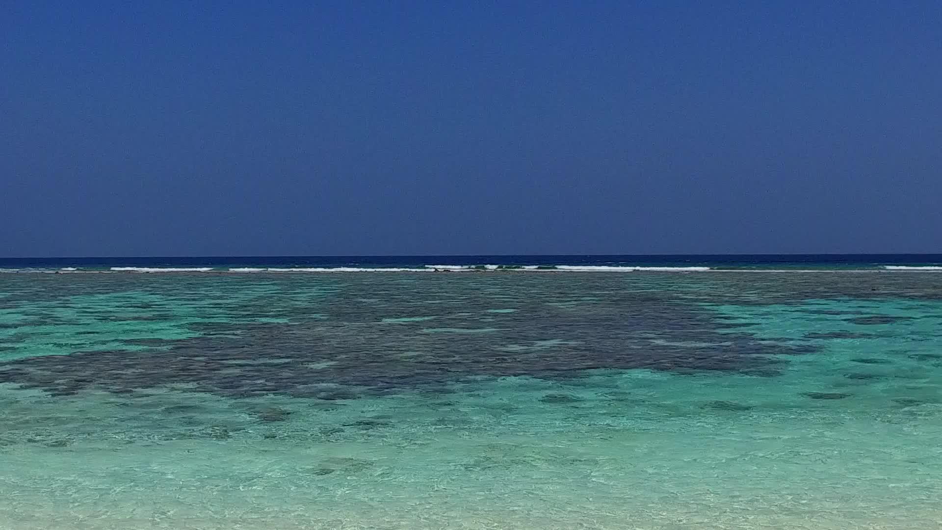 在浅海和冲浪附近享受干净的沙地背景的旅游海滩视频的预览图