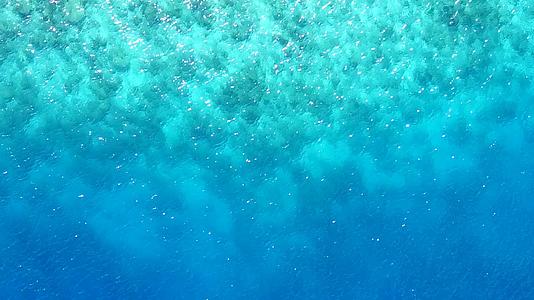 穿过蓝色的海洋在白色的海面上珊瑚礁附近有白色的沙子背景视频的预览图
