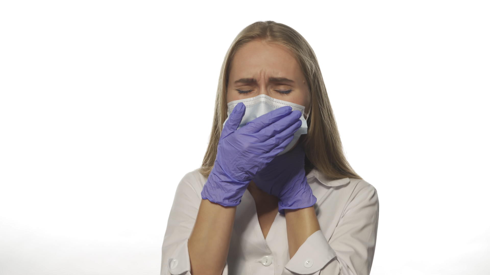 年轻护士穿着白色长袍和白色背景的医疗面具用一只手直视镜头视频的预览图
