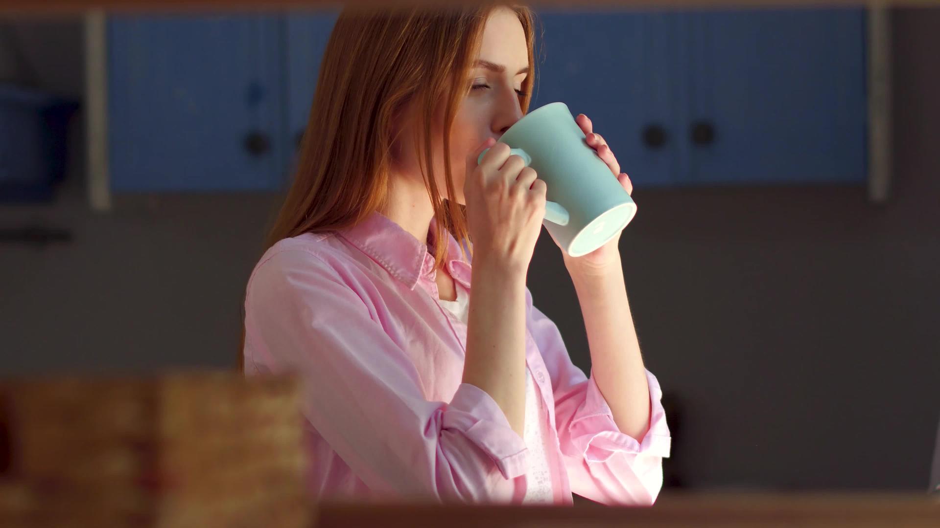 站在窗边的年轻美女喝茶做梦视频的预览图