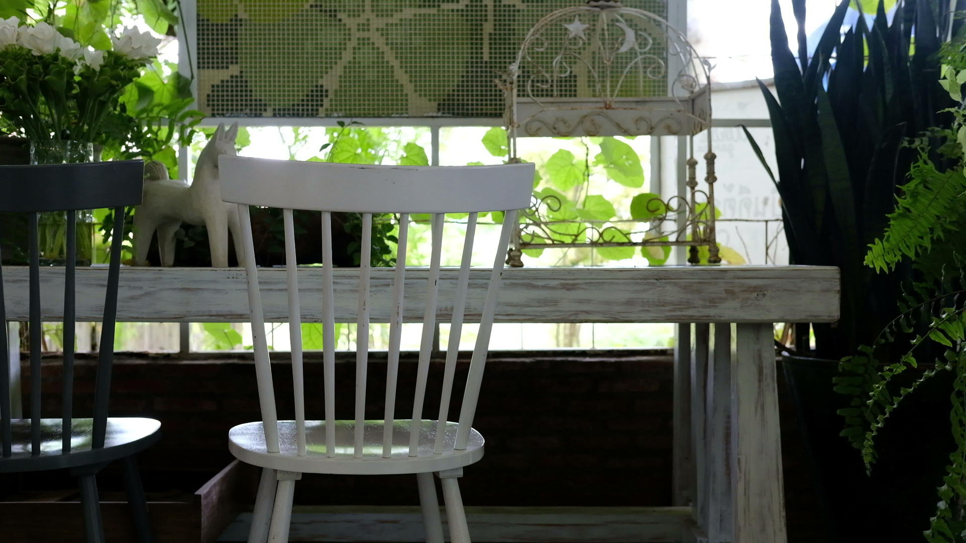 白色椅子和黑色椅子的窗户旁边有有一张木制的桌子风吹着绿叶视频的预览图