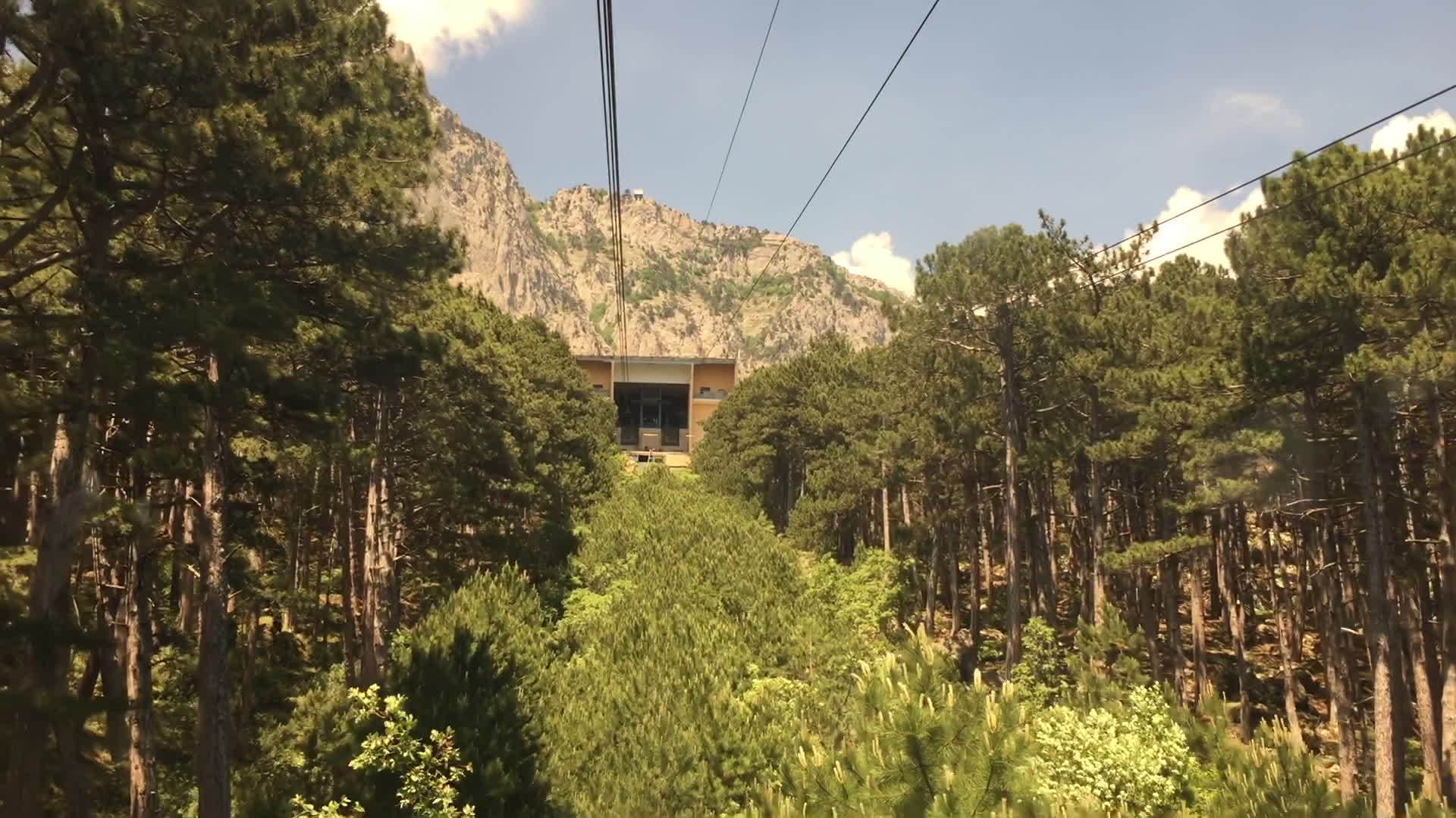 从窗户移动缆车小屋在山上的森林树木之间看缆车视频的预览图