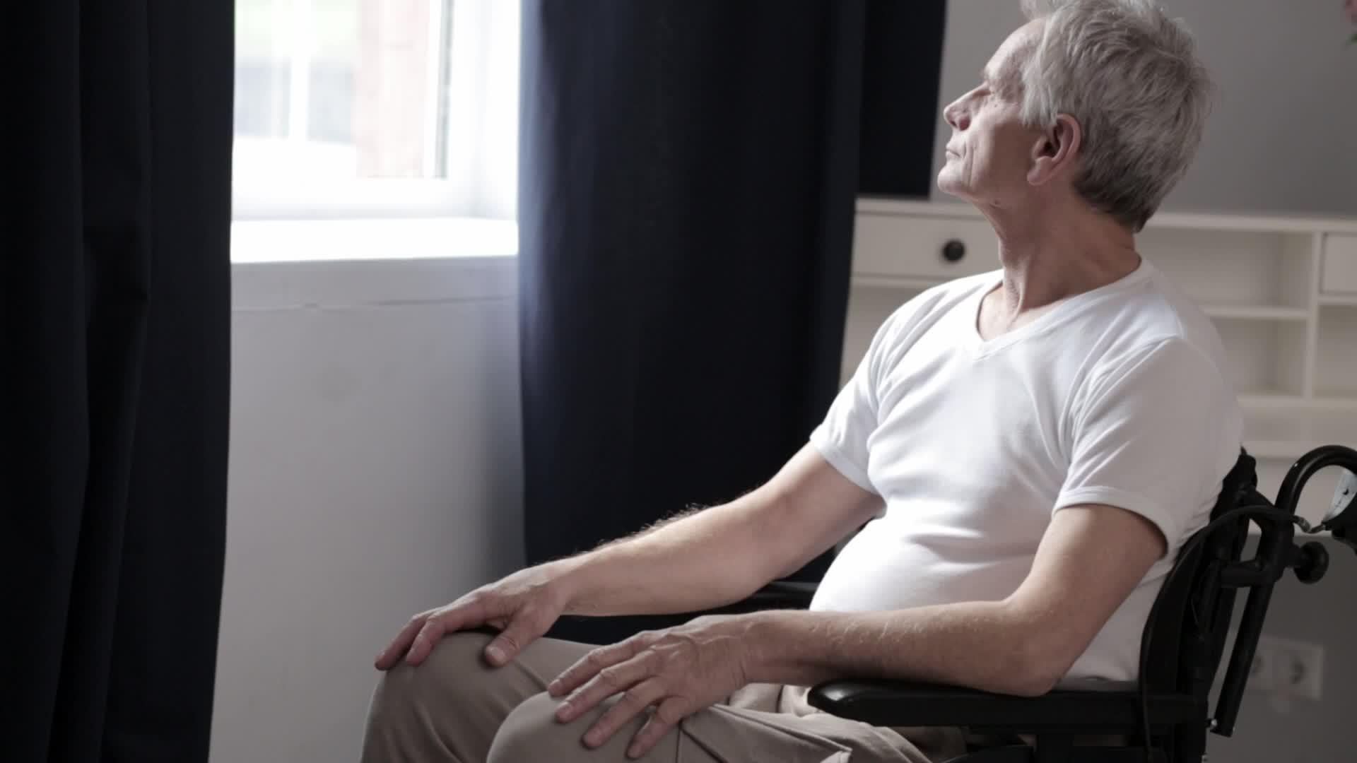 白发成年男子坐在医院的轮椅上视频的预览图