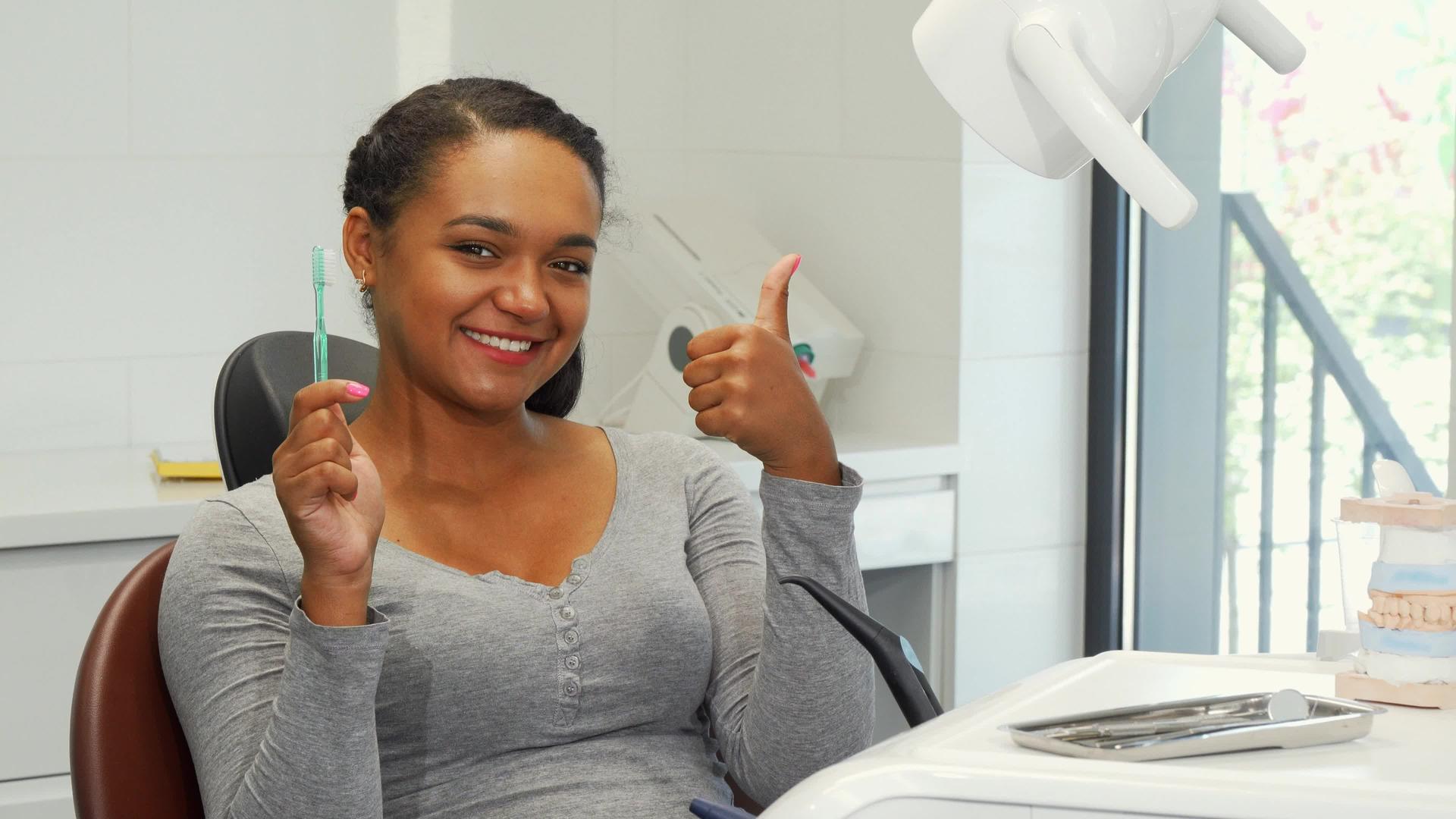 一个微笑的迷人女人举起拇指和牙刷视频的预览图