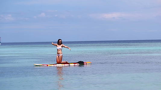 这位迷人的年轻女子站起来划船冲浪美丽的热带海洋视频的预览图