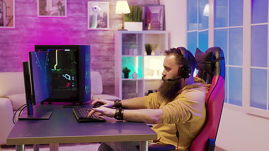 长胡子的男人在一个五颜六色的房间里玩电子游戏视频的预览图