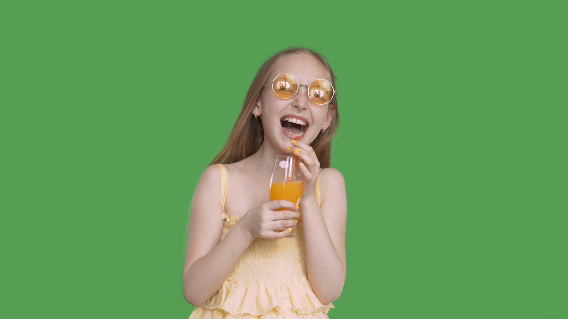 微笑的女孩手里拿着透明的绿色背景橙汁玻璃黄色眼镜视频的预览图