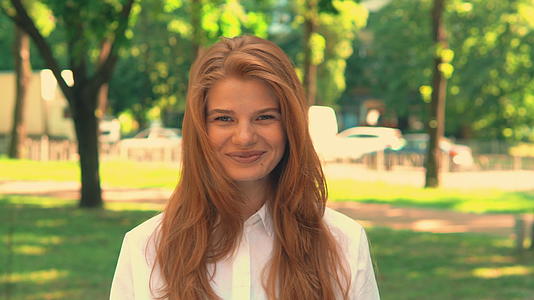 城市公园里阳光明媚的红发年轻女子视频的预览图