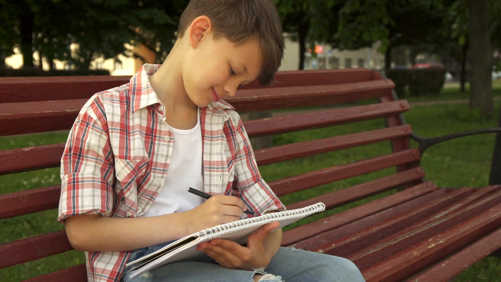 小男孩在板凳练习书上做笔记视频的预览图