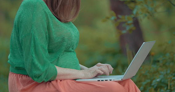 孕妇在户外用笔记本电脑工作视频的预览图