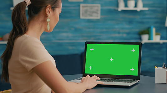 商业女性观看笔记本电脑展示和模拟绿色屏幕视频的预览图