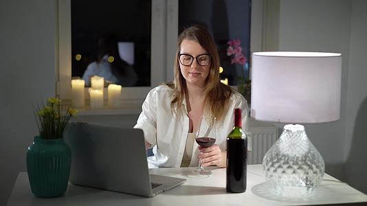 晚上年轻的年轻人在家庭办公室的电脑笔记本电脑上工作和喝酒视频的预览图