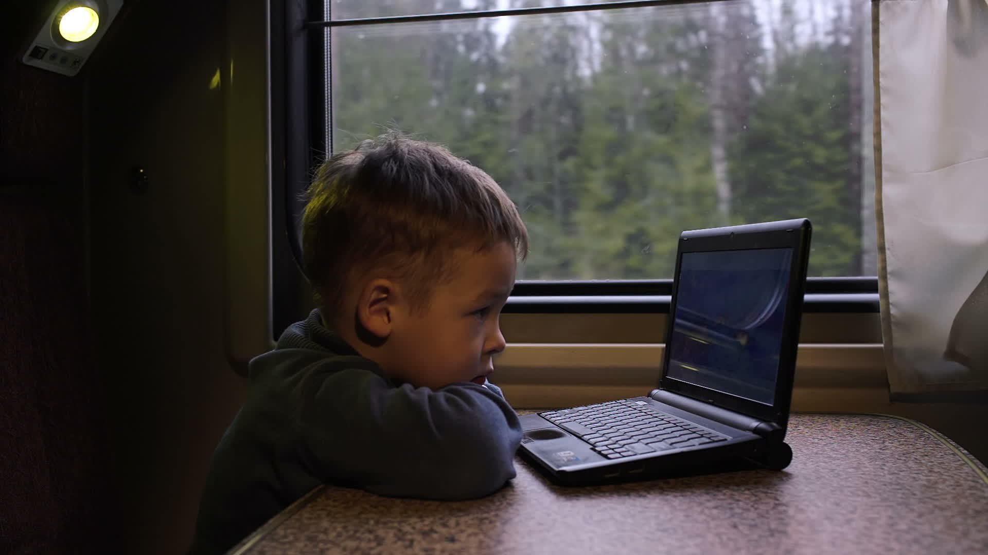 小男孩在火车上看笔记本电脑视频视频的预览图