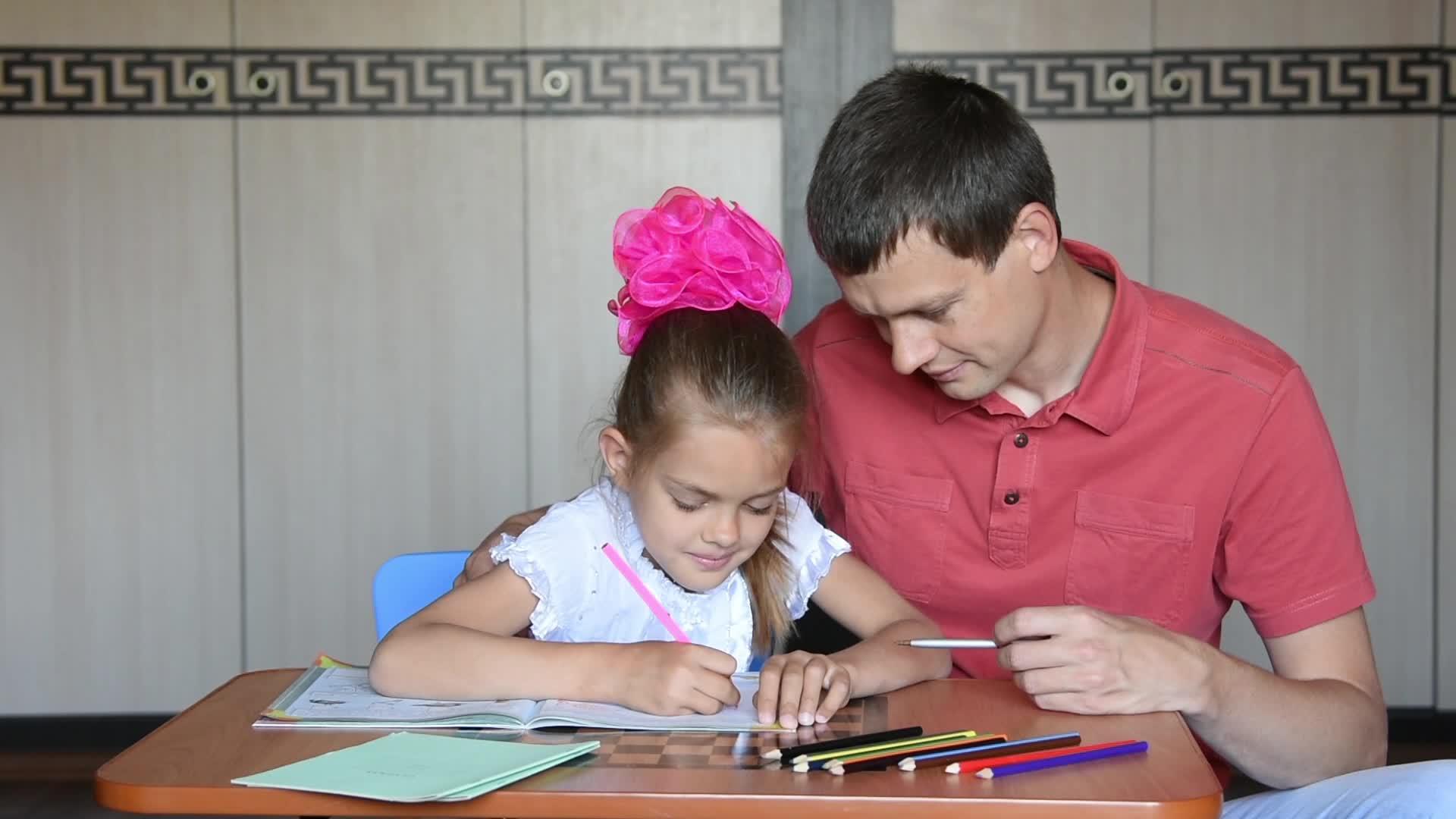 女孩和父亲在一年级解决了家庭作业愉快地看着对方视频的预览图