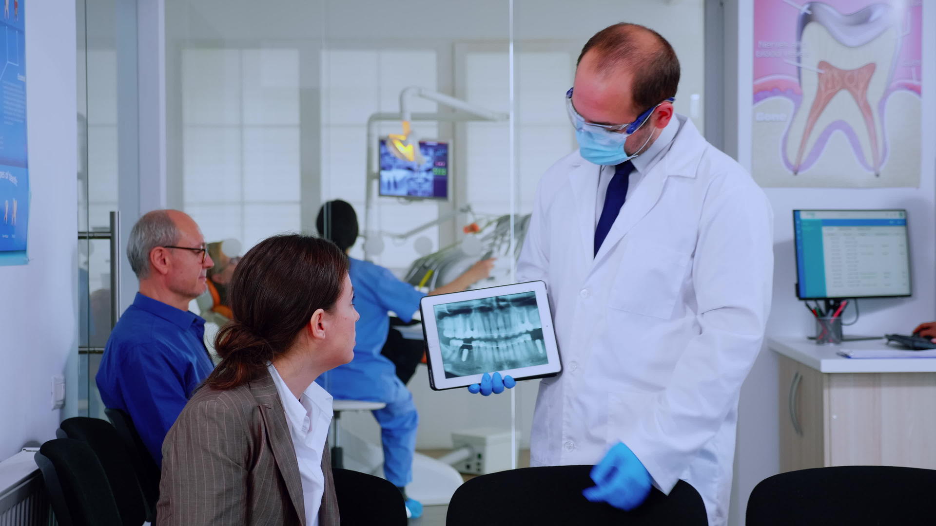 口腔科学家指向数字屏幕上向女性解释X射线视频的预览图