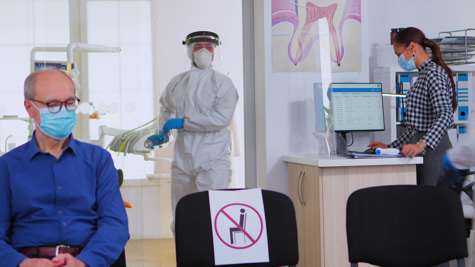 有防护服的牙医在接待室分析牙齿x光检查视频的预览图