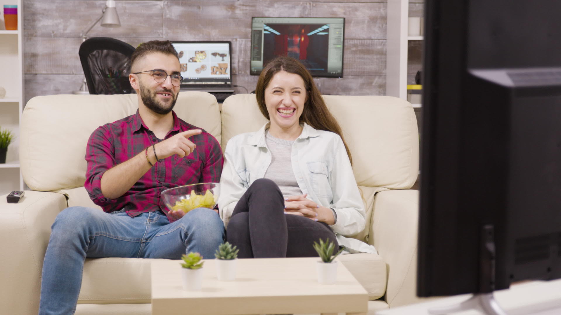 一对迷人的年轻夫妇坐在沙发上看电视视频的预览图