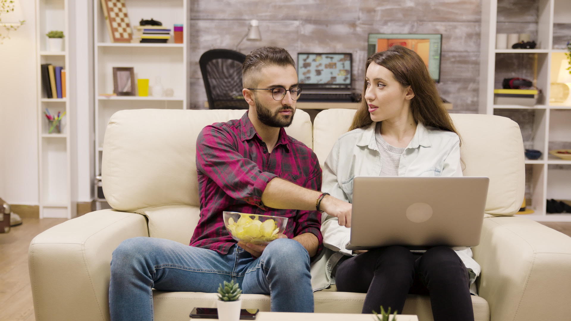 年轻快乐的夫妇坐在沙发上做网上购物视频的预览图