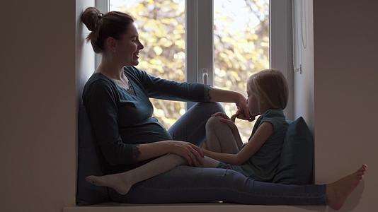 在窗台上衣服的孕妇在窗台上抚养女儿视频的预览图
