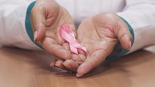 一名持有粉色丝带的女医生为了提高对乳腺癌的认识靠近她的身体视频的预览图