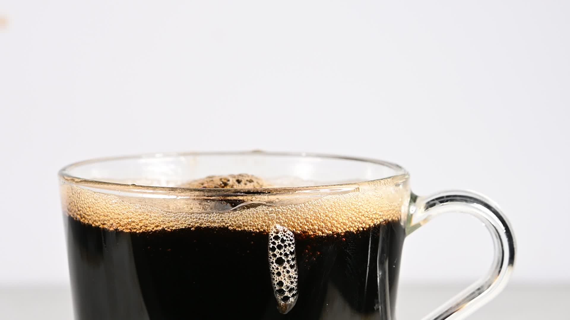 棕色糖块被扔进黑色咖啡杯视频的预览图