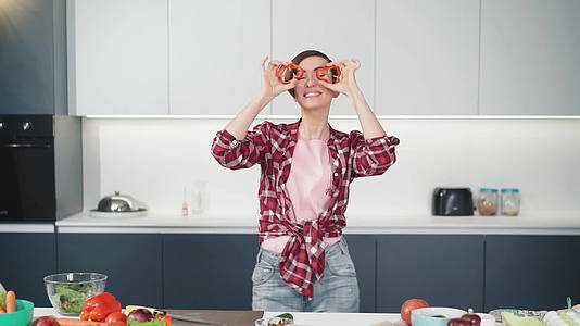 穿着红色衬衫的短发女人在白色厨房做饭时在家里切甜纸片视频的预览图