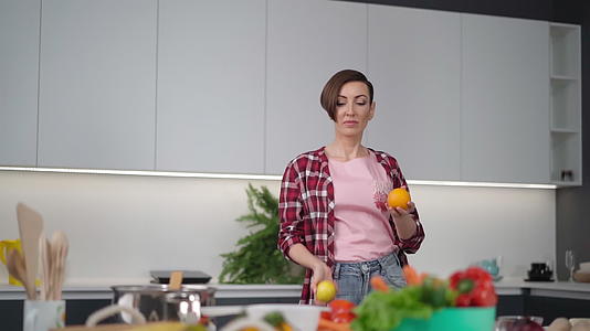 快乐的母亲手里拿着新鲜的黄色西红柿和橙色穿着格子衬衫视频的预览图