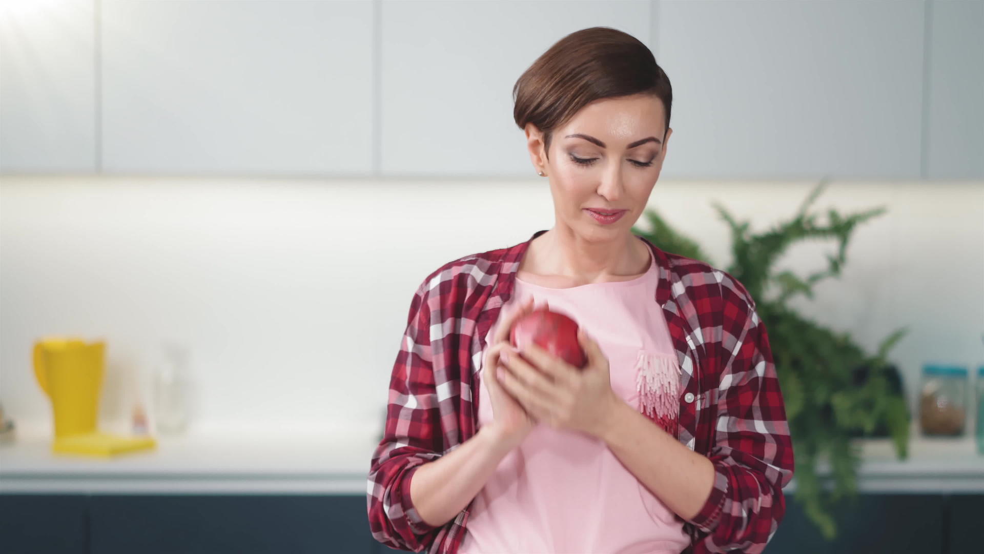 家庭主妇手里拿着新鲜的苹果穿着格子衬衫留着短发站着视频的预览图